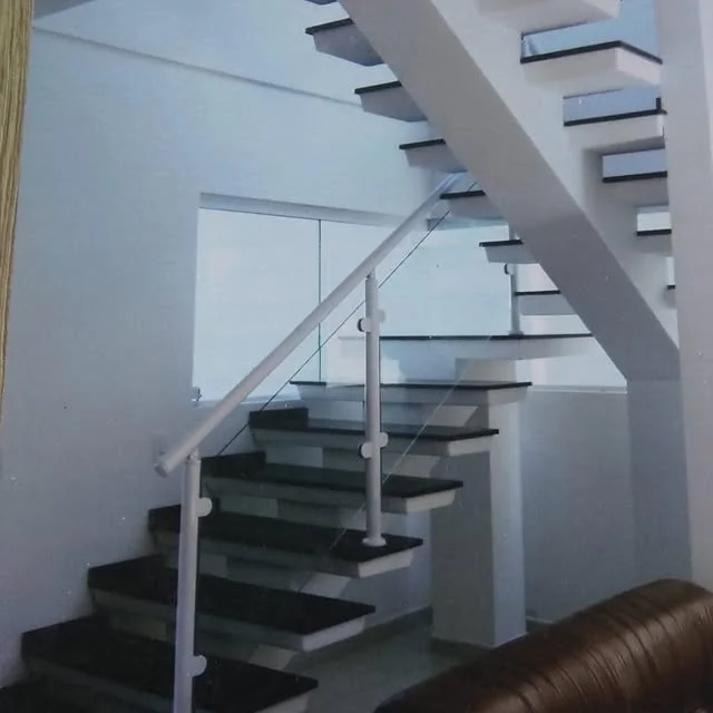 Escada de alvenaria real com degraus revestidos em preto, estrutura branca e guarda-corpo de vidro